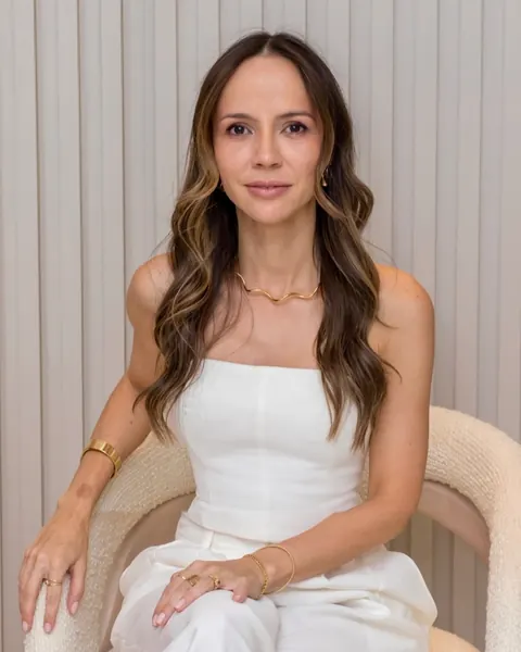 Dra. Mirele Fadel de conjunto branco, sentada numa poltrona