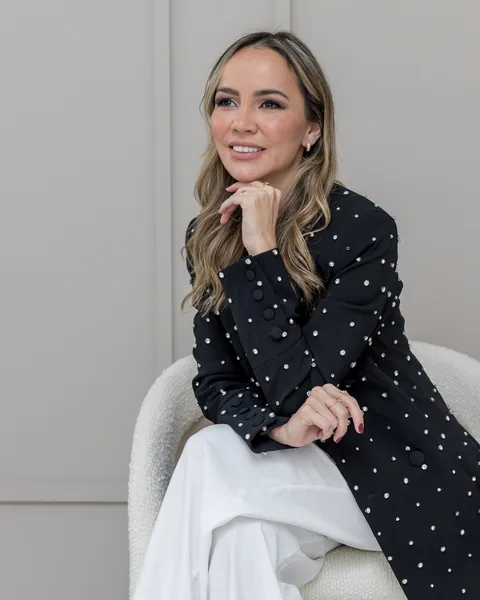 Dra. Mirele Fadel de blazer preto de poá, com a mão no queixo